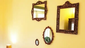 Three ornate mirrors on a yellow wall, a small framed mirror, and a lamp. - CHARMING ROOFTOP FLAT IN CITY CENTER (Catania)