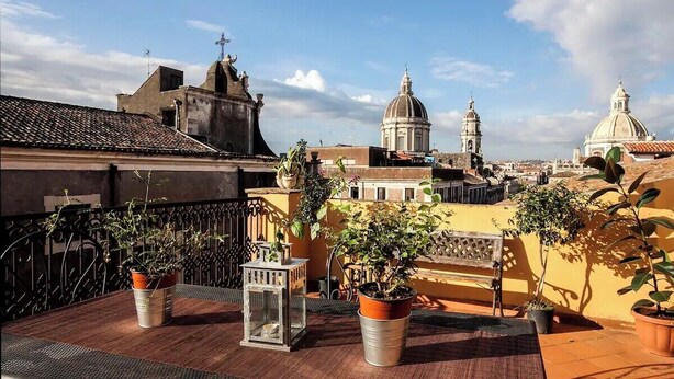 A rooftop terrace with potted plants, a metal table, and a lantern. - CHARMING ROOFTOP FLAT IN CITY CENTER (Catania)