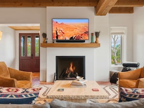 A living room with a fireplace, a television mounted on a wooden shelf, and two sofas. - Casa de Azulejos (Santa Fe)