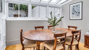 Et spiseområde med et træbord, stole og en vase med grønne planter.