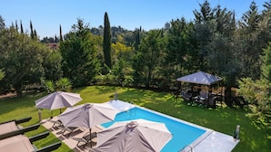 A swimming pool with lounge chairs and umbrellas, surrounded by a grassy lawn and trees. - Villa Koumquat by Villa Plus (Paleokastritsa)