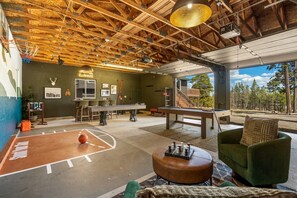 A spacious indoor area with a pool table, a basketball court, and a green sofa. - Timberveil Retreat near Breckenridge, Hot Tub, Sauna, Game Garage, Pets, Sleeps 10 (Fairplay)