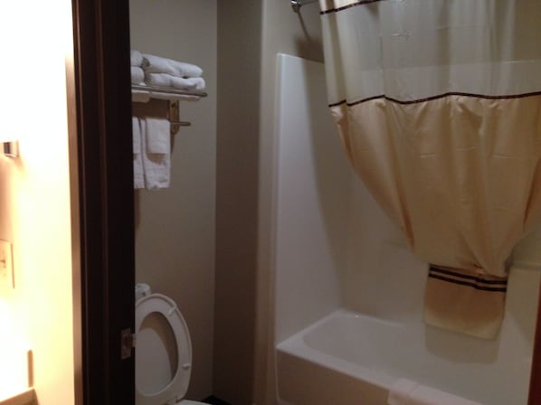 A bathroom with a toilet, a bathtub, and a shower curtain. - Logan Creek Inn (Randolph)