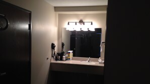 A hotel bathroom with a sink, mirror, and overhead lighting. - Logan Creek Inn (Randolph)