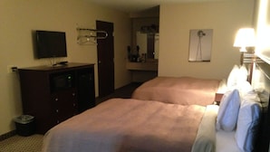 A hotel room with two beds, a TV, a desk, and a mirror. - Logan Creek Inn (Randolph)