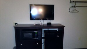 A room with a TV mounted on a wall, a microwave, and a small refrigerator. - Logan Creek Inn (Randolph)