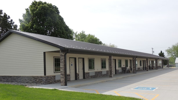 A motel with a row of rooms, a covered parking area, and a handicap-accessible parking space. - Logan Creek Inn (Randolph)