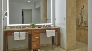 Ein modernes Badezimmer mit einem großen Spiegel, zwei Waschbecken, einer Duschkabine und einem Holzkonsolentisch mit Schubladen.