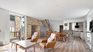 A modern living room with a fireplace, a dining area, and a kitchen with a TV.