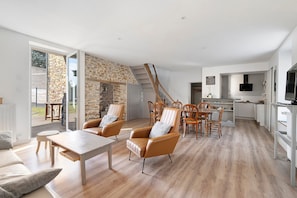 A modern living room with a fireplace, a dining area, and a kitchen with a TV.