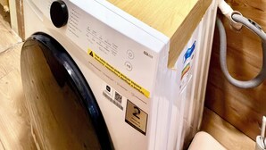 Een kleine badkamer met een wastafel, spiegel en een wasmachine.