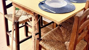 Een eettafel met blauwe placemats, houten stoelen en een hangplant.