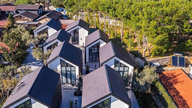 A modern residential area with multiple houses featuring geometric roofs and large windows.