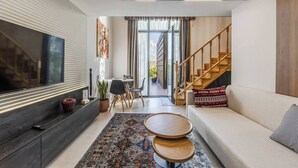 Una sala de estar moderna con un televisor grande, un sofá, una mesa de centro y un comedor con sillas.