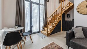 Una sala de estar moderna con una escalera, un comedor y ventanas grandes con cortinas.