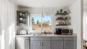A modern kitchen with grey cabinets, a built-in dishwasher, a microwave, and a window with a view of a fence and trees. - LOCATION! Uptown Retreat HotTub, Mini Putt, Fire Pit & Views (Sedona)