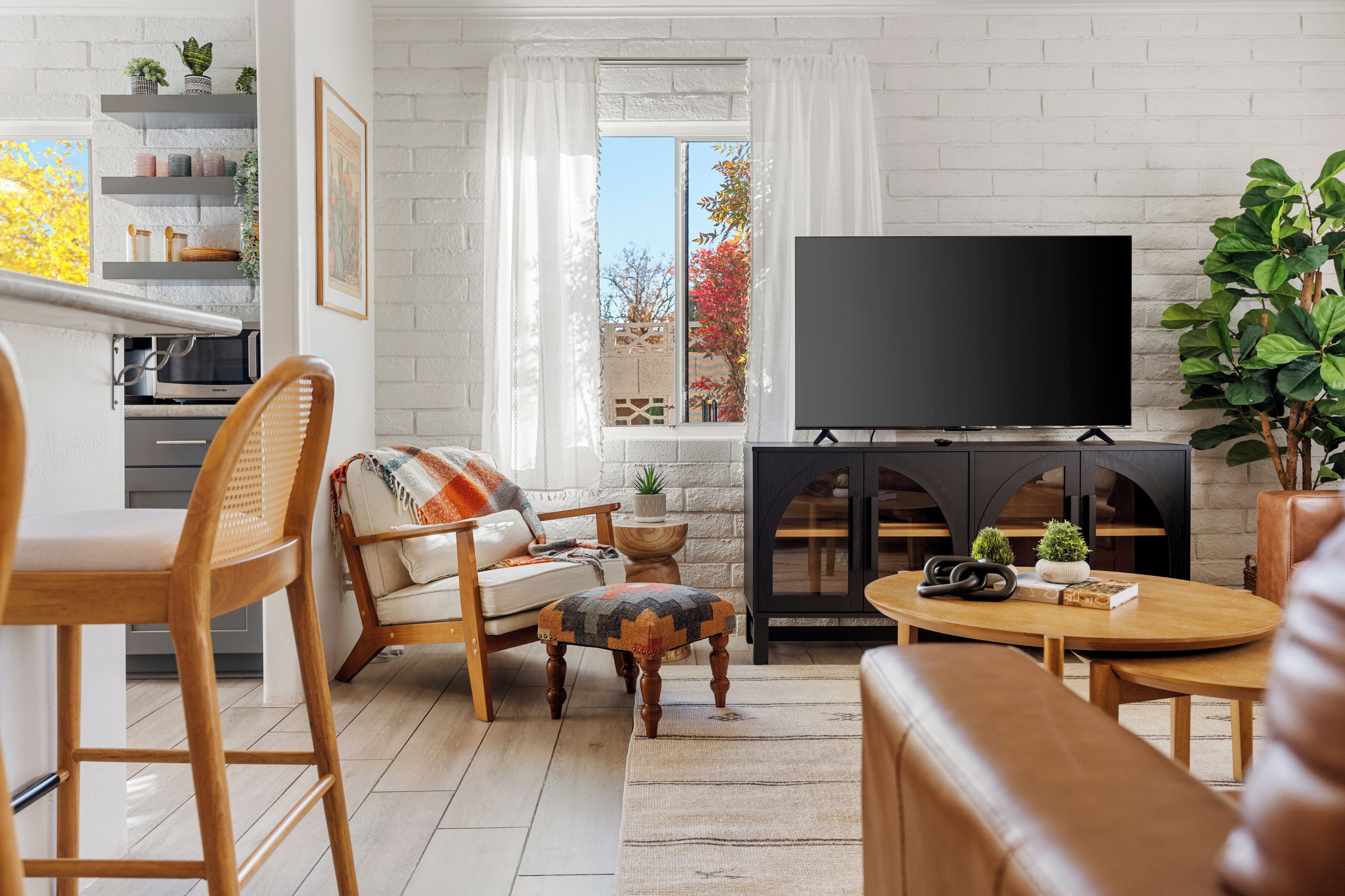 A living room with a TV, wooden furniture, a fireplace, and a view of the outdoors.