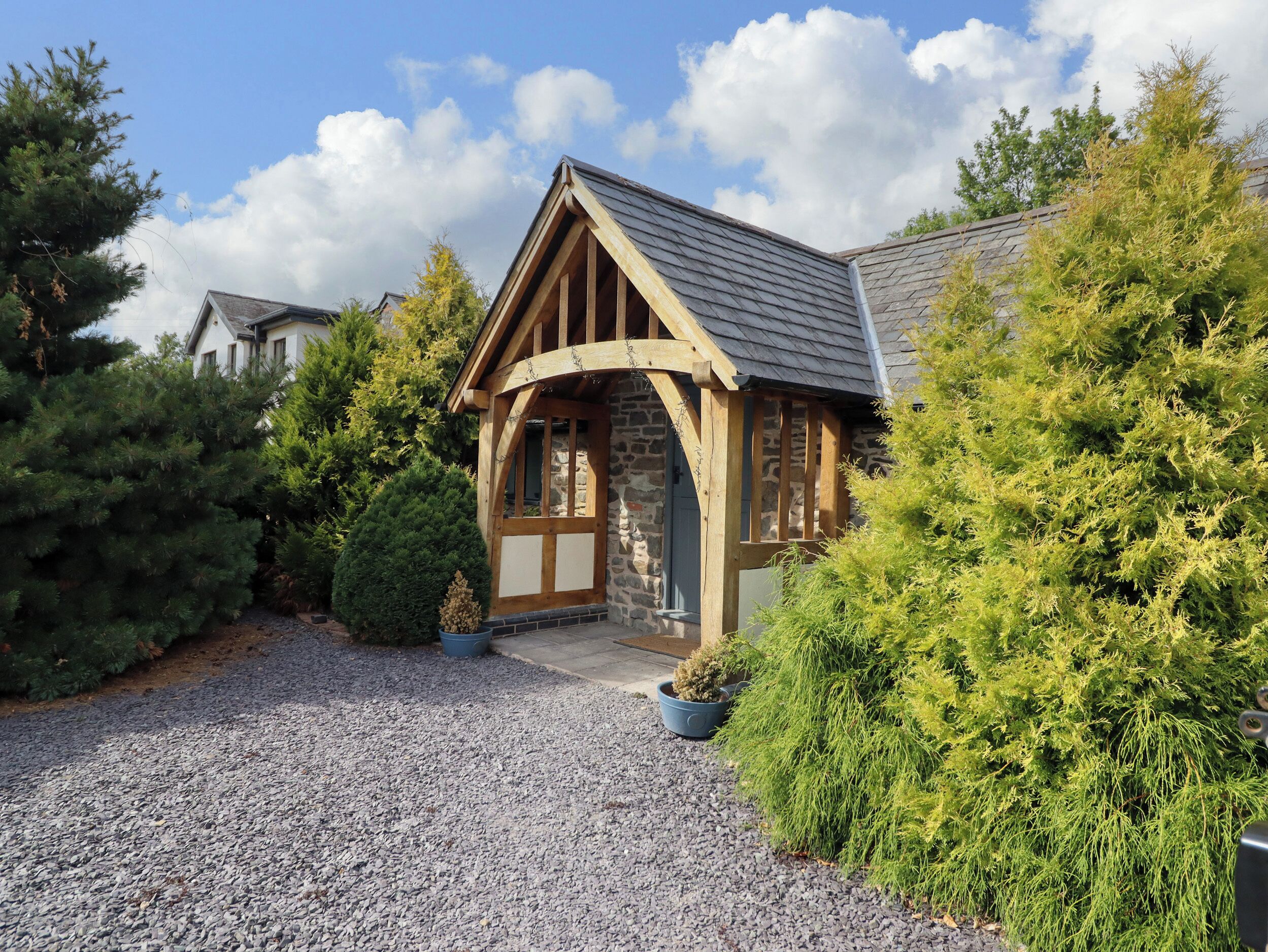 A rustic building with a stone facade, wooden beams, and a gravel driveway.