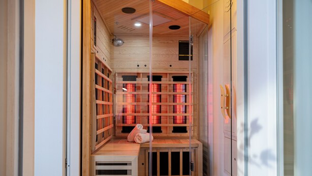 A sauna with wooden benches and glass walls, a wooden ceiling, and a small bench at the entrance. - Luv & Lee BalticLoft - loft character meets Baltic Sea flair with sauna & fireplace (Zingst)