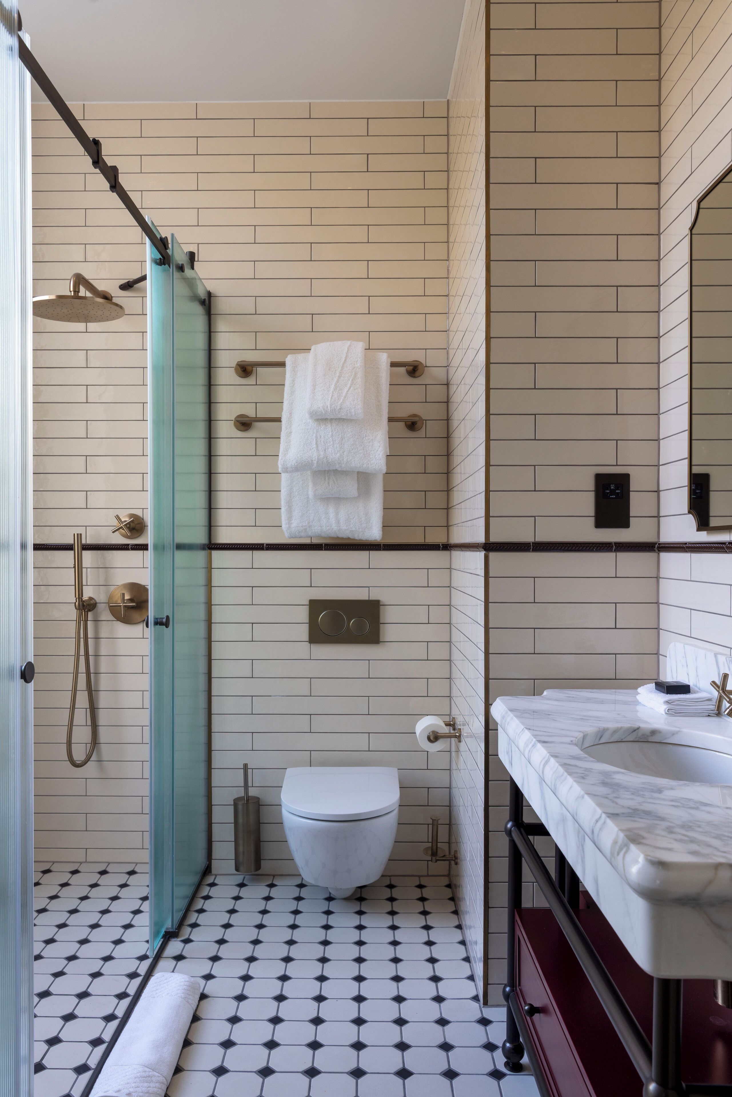 Un baño con cabina de ducha de vidrio, un inodoro blanco, un lavabo de mármol y suelo de baldosas.