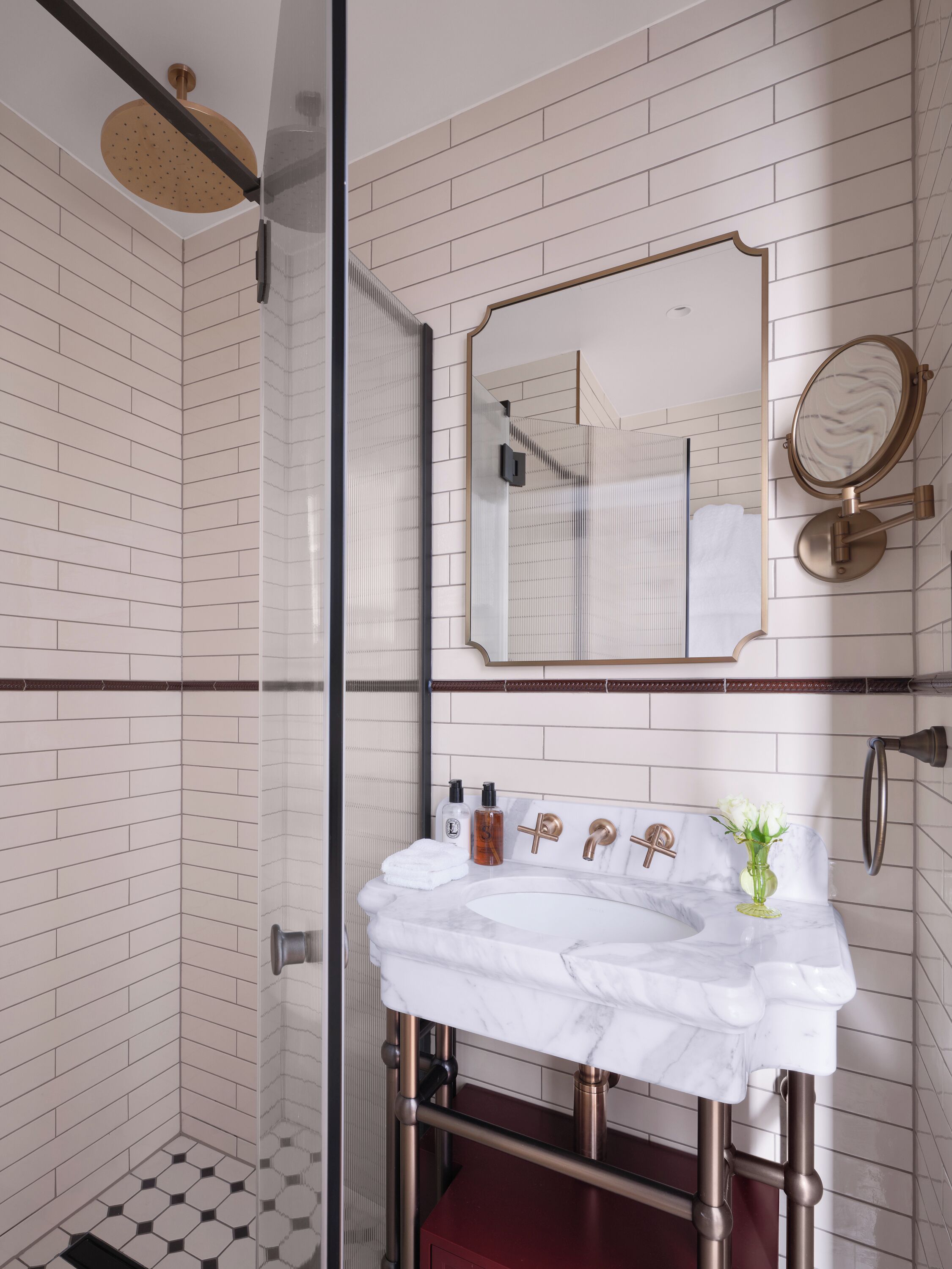 Une salle de bain moderne avec une douche à parois de verre, un lavabo en marbre et un grand miroir.