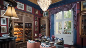 A library with bookshelves, a table with chairs, and a large window with curtains. - Bertrand's Townhouse (London)
