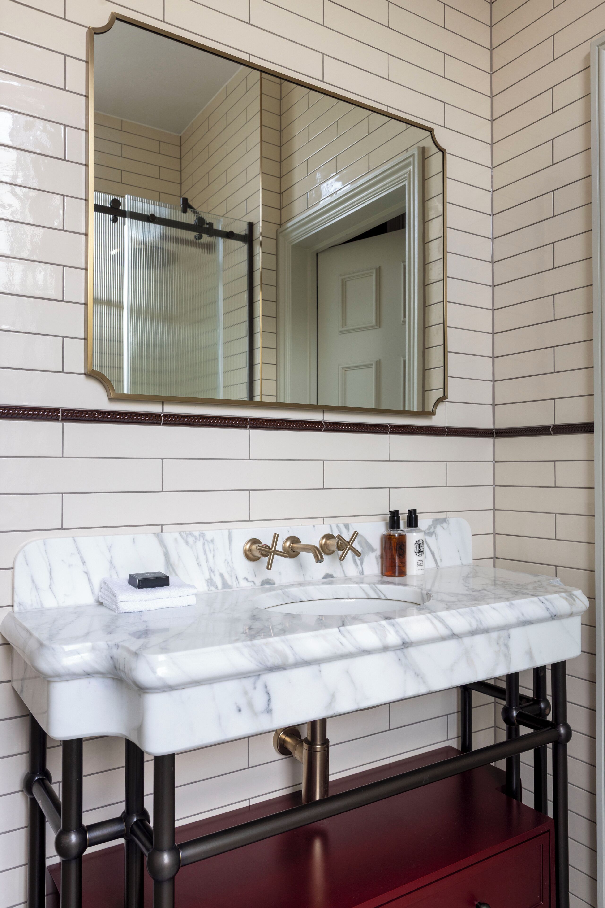 Une salle de bain avec un lavabo en marbre, un grand miroir et un meuble rouge en dessous.