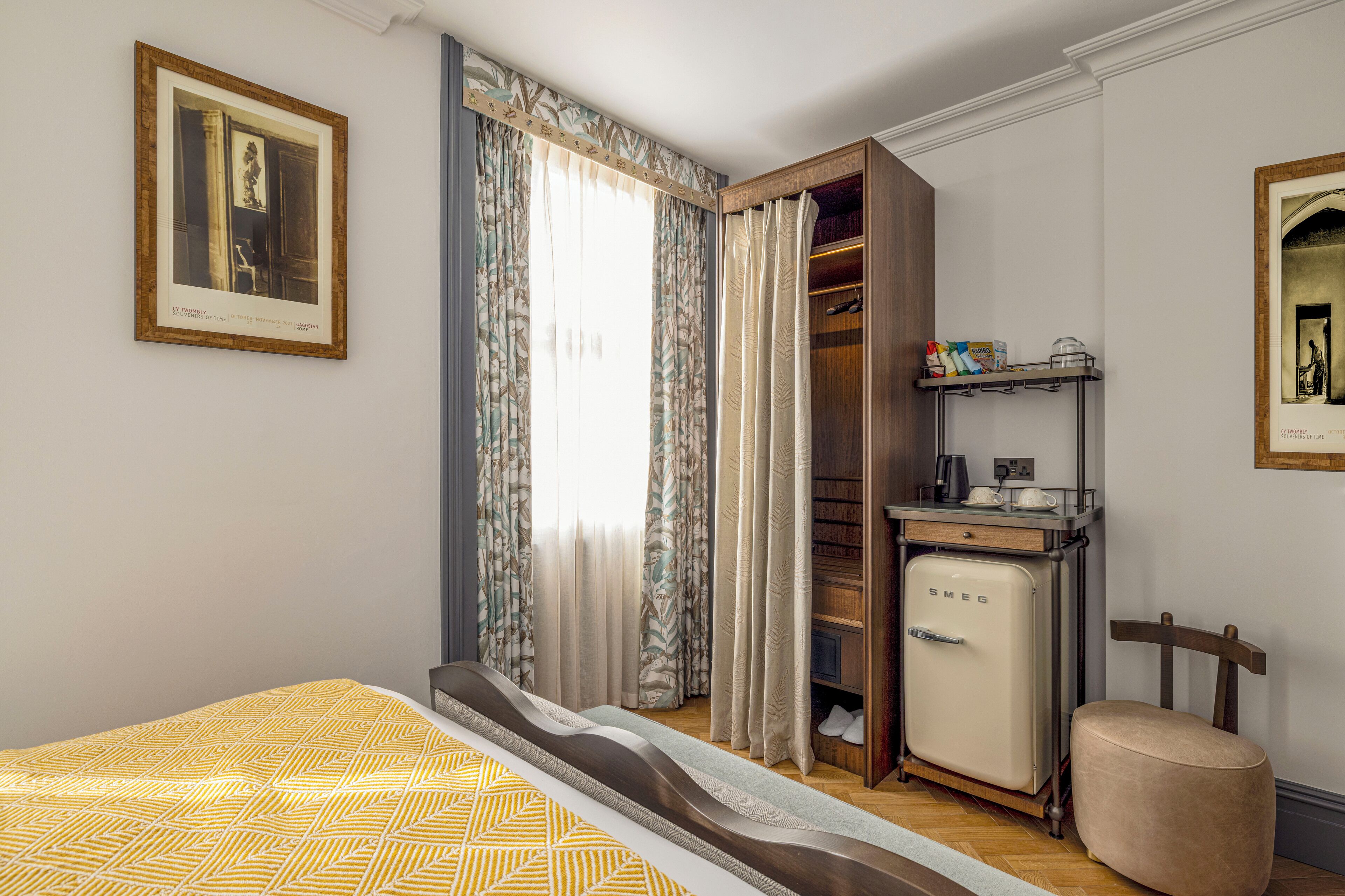 A bedroom with a bed, a wardrobe, a small kitchenette, and a chair.