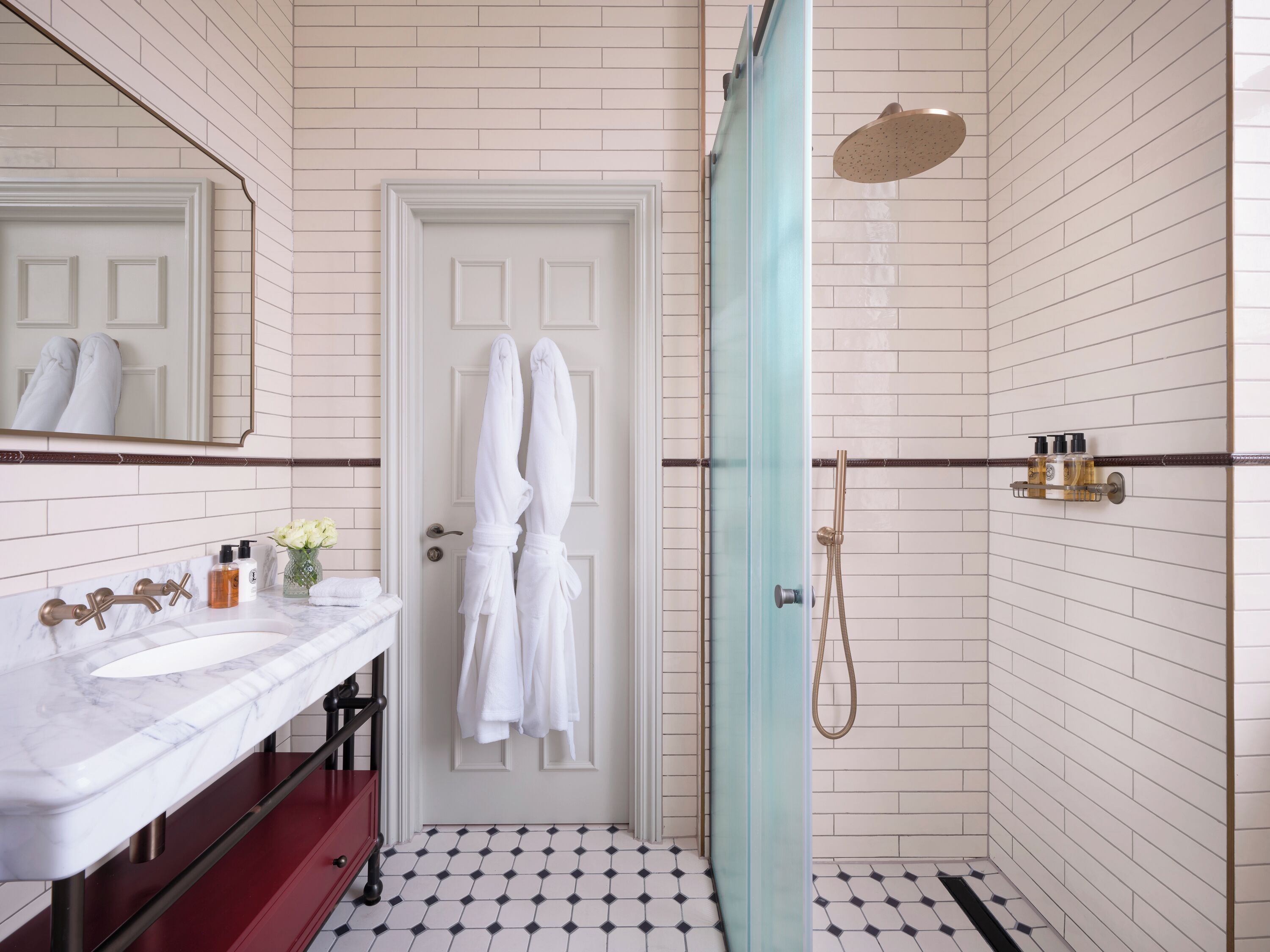 A bathroom with a white door, a marble sink, a red cabinet, and a shower area with a glass door.