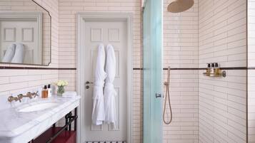 A bathroom with a white door, a marble sink, a red cabinet, and a shower area with a glass door.
