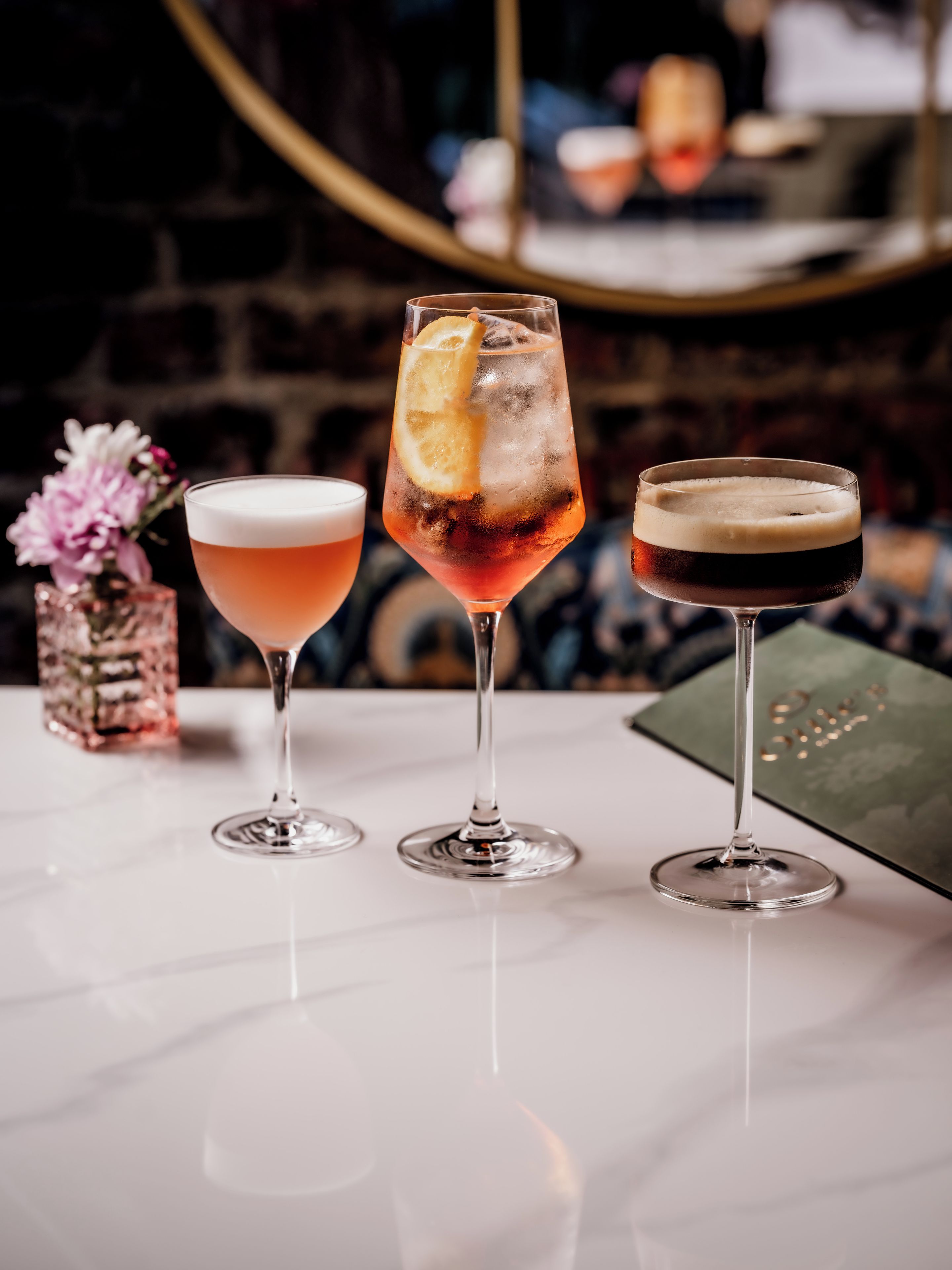 Trois verres contenant différentes boissons sont posés sur une table en marbre.