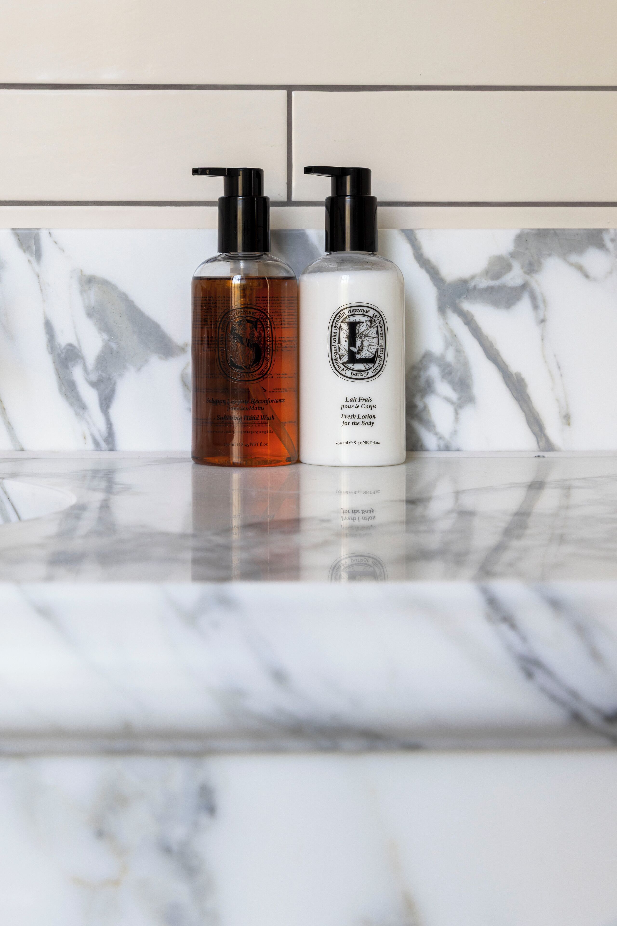 Two bottles of lotion on a marble countertop.