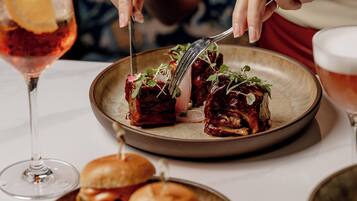 A dining table with a plate of food, a glass of drink, and a burger.