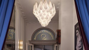 A grand hallway with a chandelier, a staircase, a checkered floor, and a sign reading "Bertrand's Townhouse". - Bertrand's Townhouse (London)