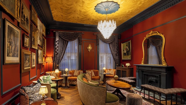 A luxurious room with a fireplace, multiple seating areas, and a chandelier. - Bertrand's Townhouse (London)