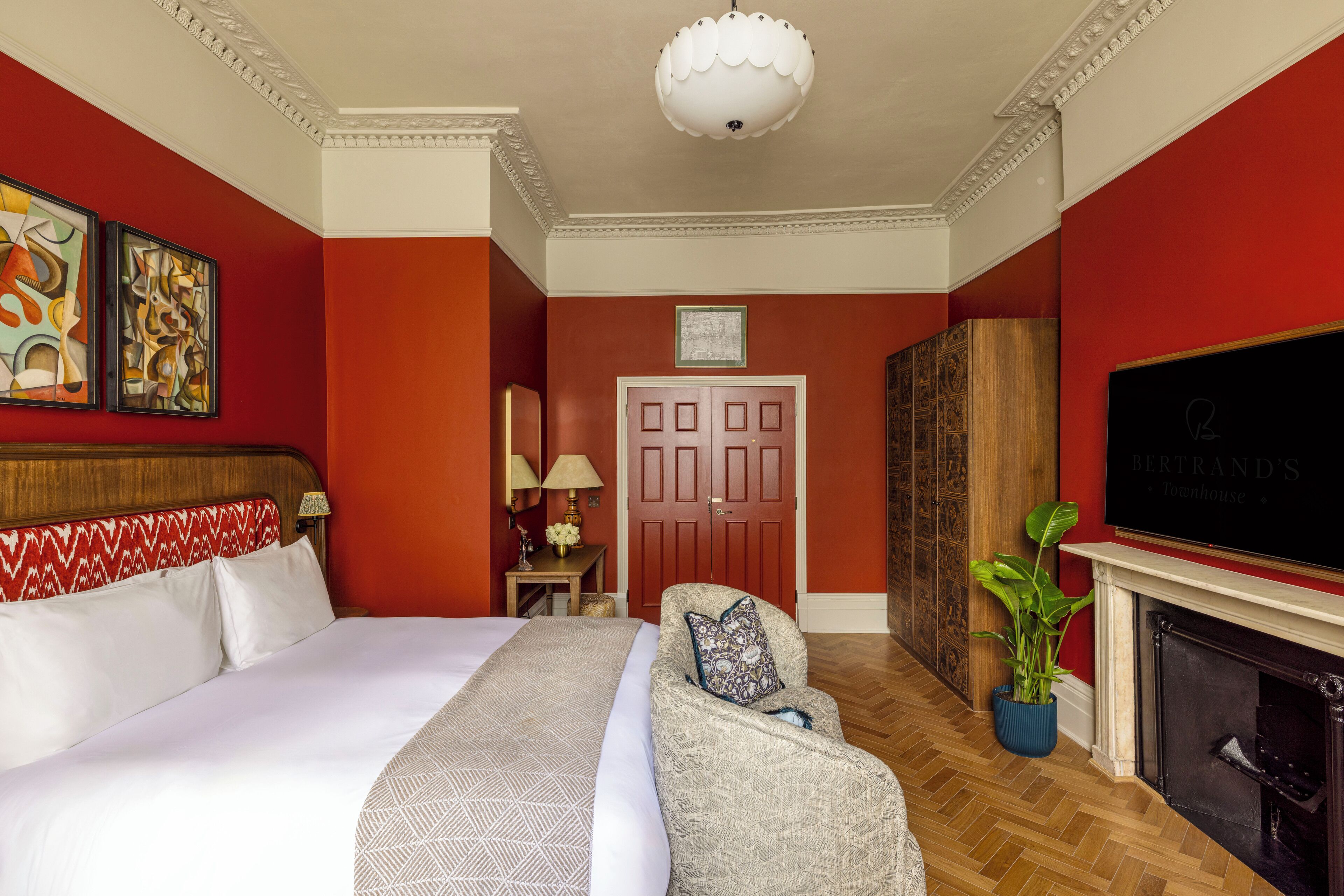 A hotel room with a large bed, a sofa, a fireplace, and a television.