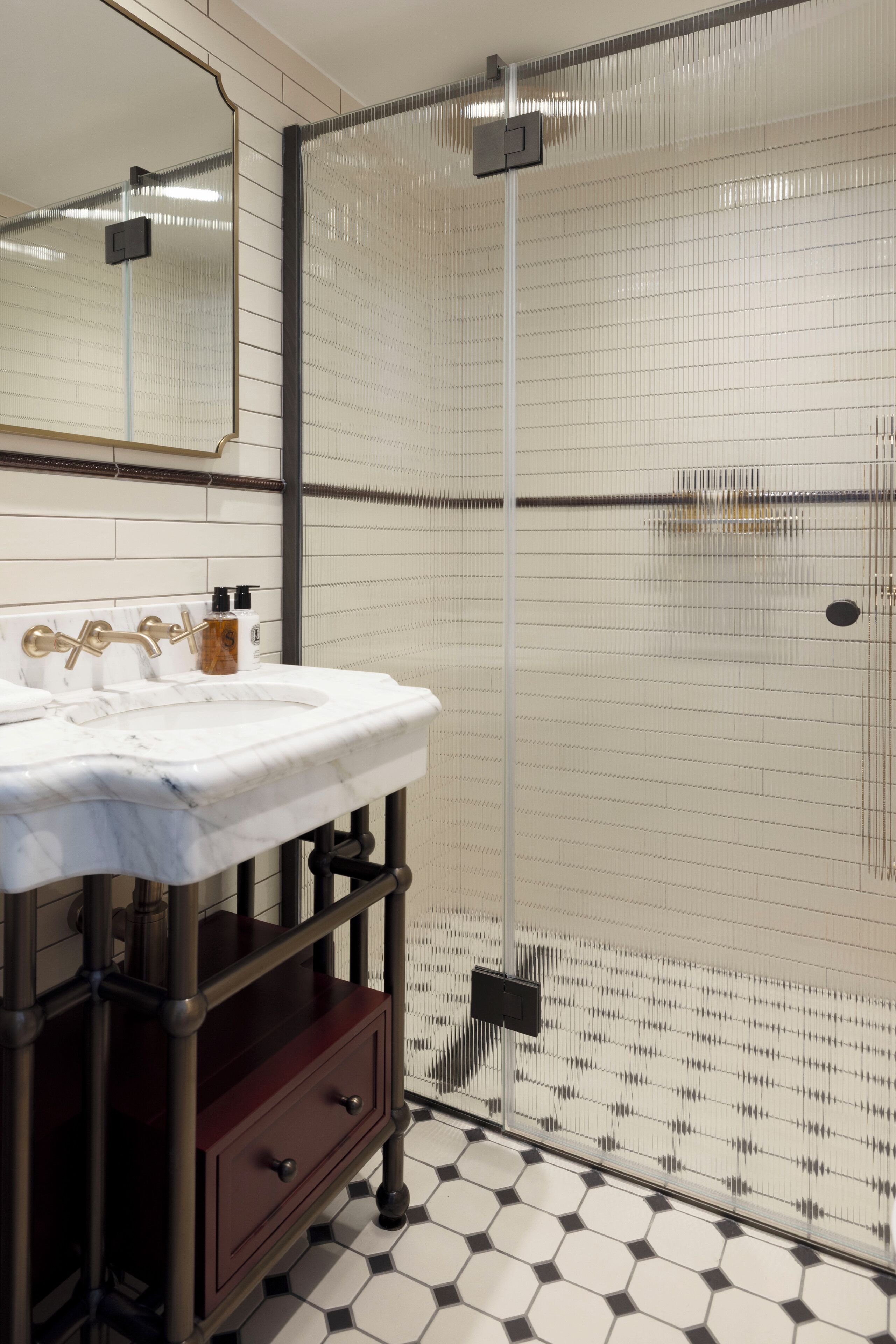 A bathroom with a white sink, a mirror, and a shower enclosure with a glass door.