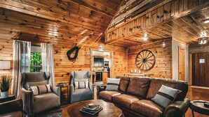 A cozy wooden interior with a leather sofa, armchairs, and a coffee table. - NEW! The Cowboy-5BR Cabin w/HT, Game Room & Pool Access (Sevierville)
