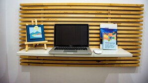 Un ordinateur portable est posé sur une table blanche, avec un mur en lambris de bois derrière.