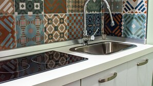 A kitchen with a modern design, featuring a stainless steel sink and a patterned backsplash. - Inner Naples (Naples)