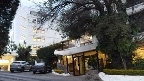 A modern hotel with a glass facade, a stone entrance, and a snow-covered ground. - Hotel Miralvalle (San Pedro Sacatepequez)