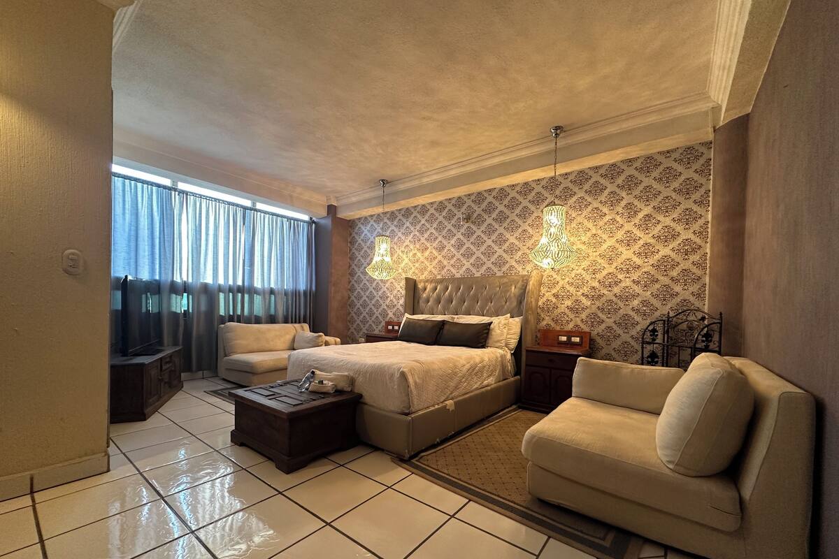 Une chambre spacieuse avec un grand lit, un canapé et une télévision.
