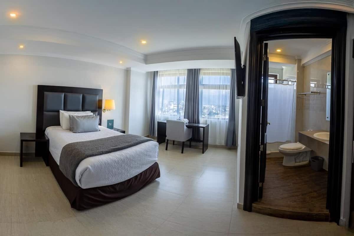 Une chambre d’hôtel moderne, dotée d’un grand lit, d’un bureau et d’une salle de bain.
