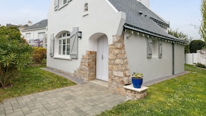 A single-story house with a white exterior, stone foundation, and a grey roof.