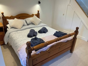 A neatly made bed with a wooden headboard, a bedside table, and a wall-mounted light. - The Apple Store (Tarporley)