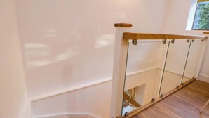 A wooden staircase with glass railings and a carpeted landing. - The Apple Store (Tarporley)