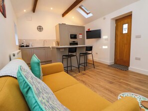 A compact living space with a sofa, a small kitchen area, and a dining table with two chairs.