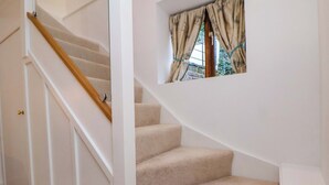 A carpeted staircase with a wooden handrail and a window with curtains. - The Apple Store (Tarporley)