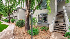 A residential building with a covered outdoor staircase, a landscaped garden with trees and shrubs, and a clear view of the building's exterior. - 2bd/2ba North Scottsdale Condo (Scottsdale)
