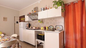 A compact kitchen with white cabinets, a microwave, and a small table.